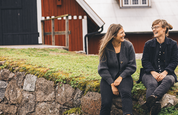 Susanna Olsson och Rebecka Angeldahl i glatt samspråk utanför en ladugårdsbyggnad