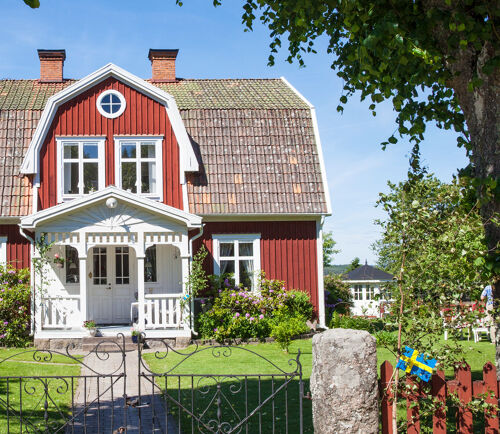 Rött hus med vita knutar på svensk landsbygd