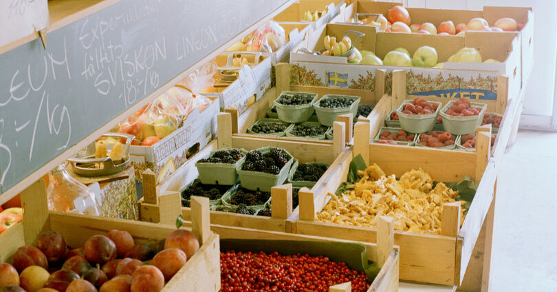 Gårdsbutik med grönsaker och frukt i trälådor