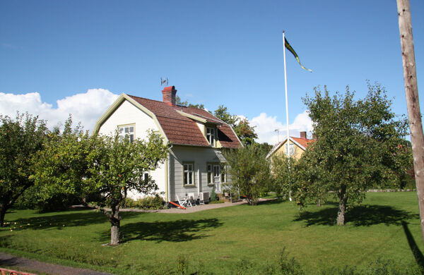 Villa med somrig trädgård och flaggstång