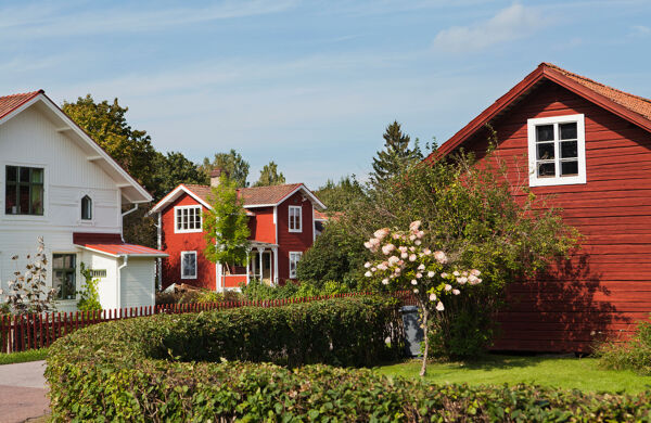 Villakvarter med röda och vita hus med grön häck i förgrunden