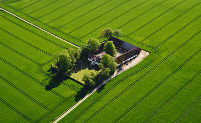 Flygfoto över gård omgiven av klargröna åkrar