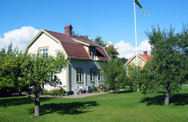 Vit villa i trädgård med äppelträd och flaggstång