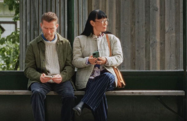 Två personer på en bänk med mobiltelefoner i händerna